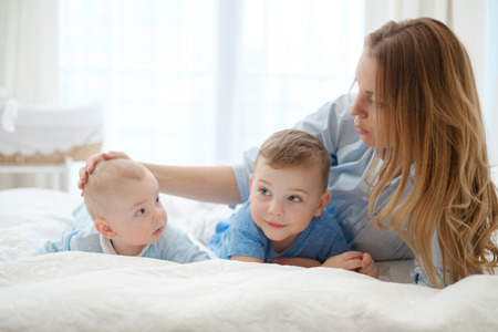 Happy middle aged mother with her children in a bed
