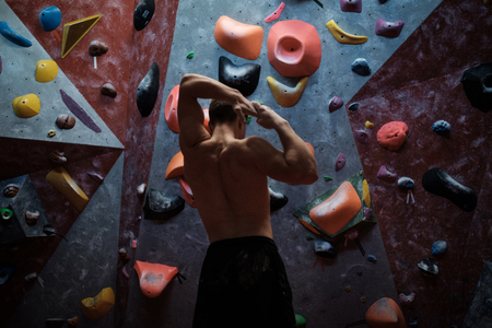 Athletic man stretching before climbing in a bouldering gymの写真素材