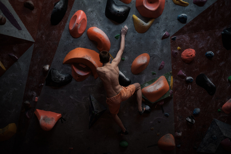 Athletic man practicing in a bouldering gymの写真素材