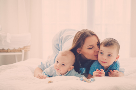 Happy middle aged mother with her children in a bedの写真素材