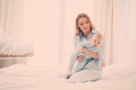 Happy middle aged mother with her child in a bedの写真素材
