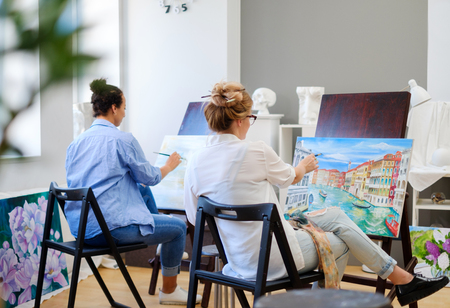 Creative painter and her protege working in a studioの写真素材
