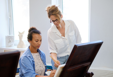 Creative painter and her protege working in a studioの写真素材