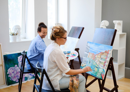 Creative painter and her protege working in a studioの写真素材