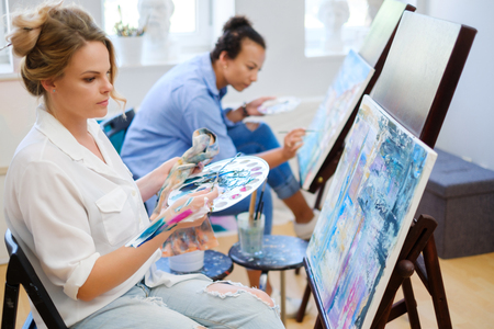 Creative painter and her protege working in a studioの写真素材