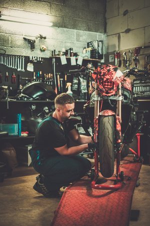 Mechanic repairing a motorcycle in a workshopの写真素材