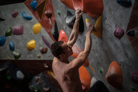 Athletic man practicing in a bouldering gymの写真素材