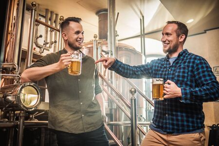 Two men tasting fresh beer in a breweryの写真素材