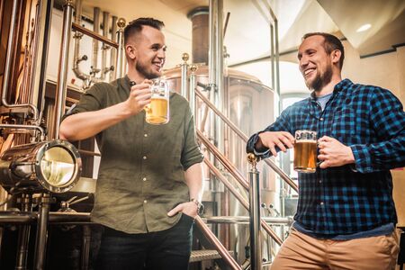 Two men tasting fresh beer in a breweryの写真素材