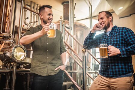 Three men tasting fresh beer in a breweryの写真素材