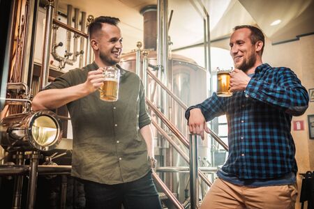 Two men tasting fresh beer in a breweryの写真素材