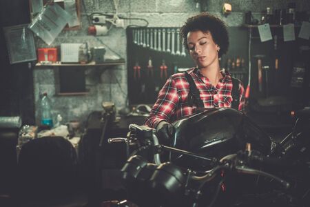 African american woman mechanic repairing a motorcycle in a workshopの写真素材