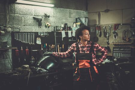 African american woman mechanic repairing a motorcycle in a workshopの写真素材