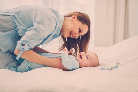 Happy middle aged mother with her child in a bedの写真素材