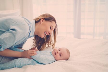 Happy middle aged mother with her child in a bedの写真素材