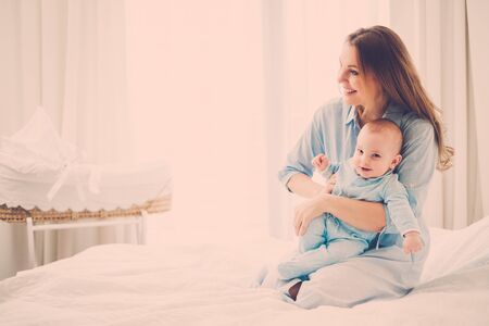 Happy middle aged mother with her child in a bedの写真素材