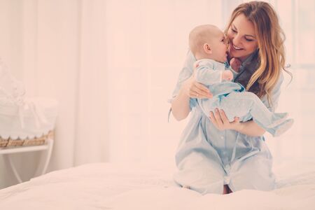 Happy middle aged mother with her child in a bedの写真素材