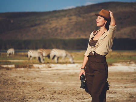 Beautiful woman with binoculars at savanna in Kenyaの写真素材