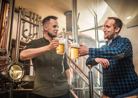 Two men tasting fresh beer in a breweryの写真素材