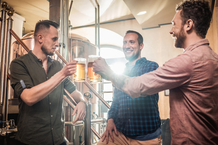 Three men tasting fresh beer in a brewery