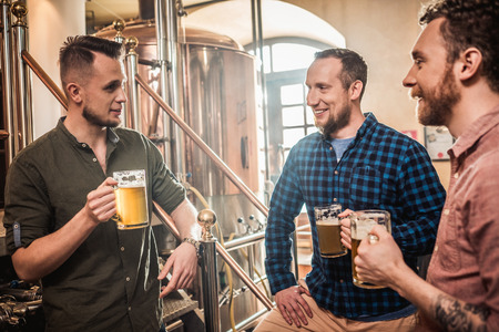 Three men tasting fresh beer in a breweryの写真素材