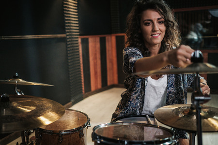 Woman playing drums during music band rehearsalの写真素材