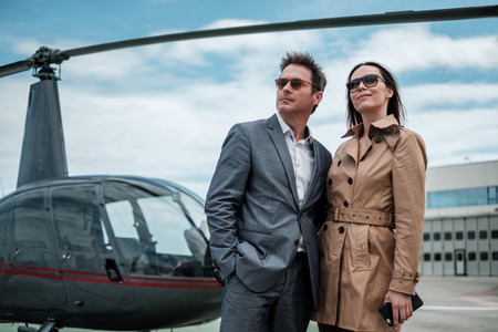 Young business couple near private helicopter