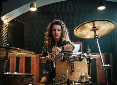Woman playing drums during music band rehearsalの写真素材