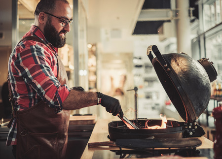 Chef preparing charcoals before grilling in a restaurantの写真素材