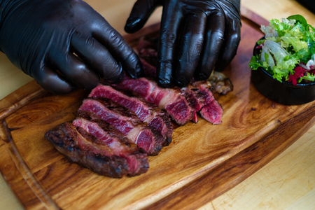 Serving freshly cooked beef steak on a wooden boardの写真素材