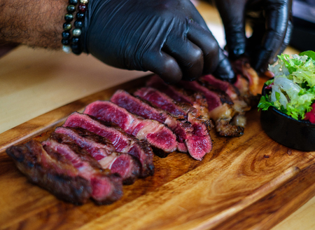 Serving freshly cooked beef steak on a wooden boardの写真素材