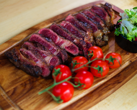 Serving freshly cooked beef steak on a wooden boardの写真素材