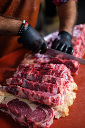 Chef cutting beef steakes in a restaurantの写真素材