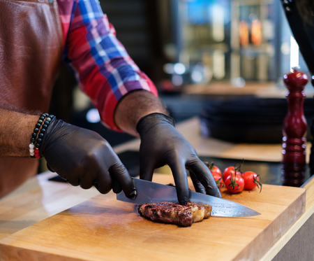 Cutting freshly cooked beef steak on a wooden boardの写真素材