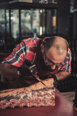 Chef cutting beef carcass in a restaurantの写真素材
