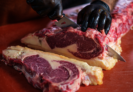 Chef cutting beef steakes in a restaurantの写真素材