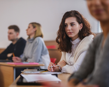 Beautiful girl taking notes in multinational group of students in an auditoriumの写真素材