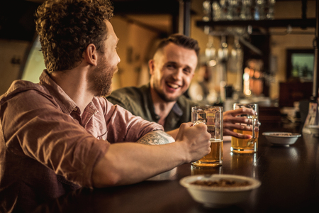 Cheerful friends drinking draft beer in a pubの写真素材