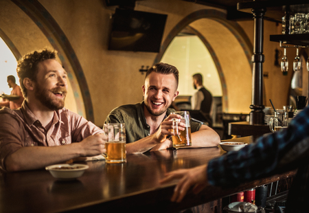 Cheerful friends drinking draft beer in a pubの写真素材