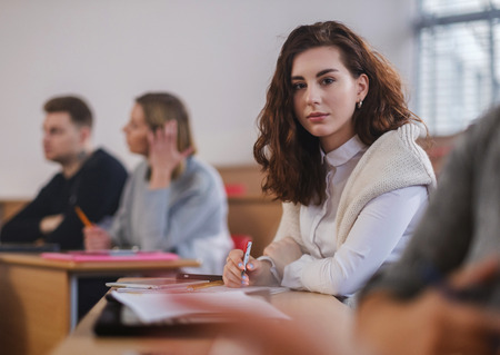 Beautiful girl taking notes in multinational group of students in an auditoriumの写真素材