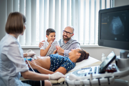 Pregnant woman and her family on utltrasonographic examination at hospitalの写真素材