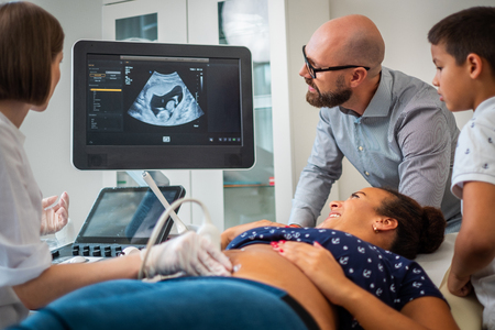 Pregnant woman and her family on utltrasonographic examination at hospitalの写真素材