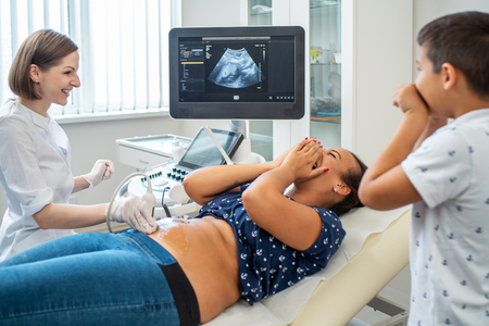Pregnant woman and her son on utltrasonographic examination at hospitalの写真素材
