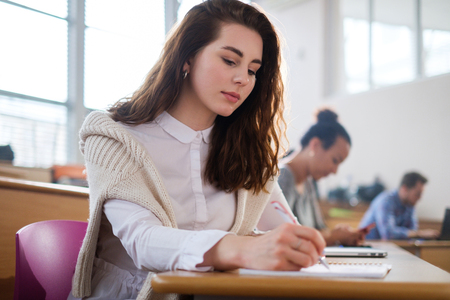 Beautiful girl taking notes in multinational group of students in an auditoriumの写真素材