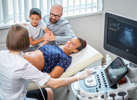 Pregnant woman and her family on utltrasonographic examination at hospitalの写真素材
