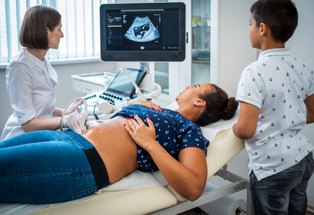Pregnant woman and her son on utltrasonographic examination at hospitalの写真素材