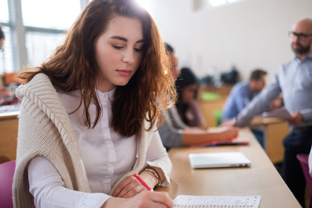 Beautiful girl taking notes in multinational group of students in an auditoriumの写真素材