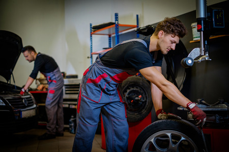 Car mechanic mounts tire on wheel in a workshopの写真素材