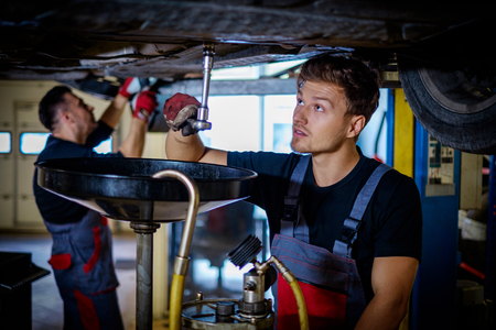 Car mechanic changes oil in a workshopの写真素材