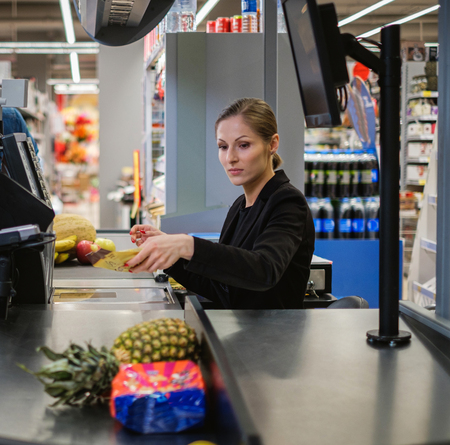 Woman cashier working in a grocery storeの写真素材